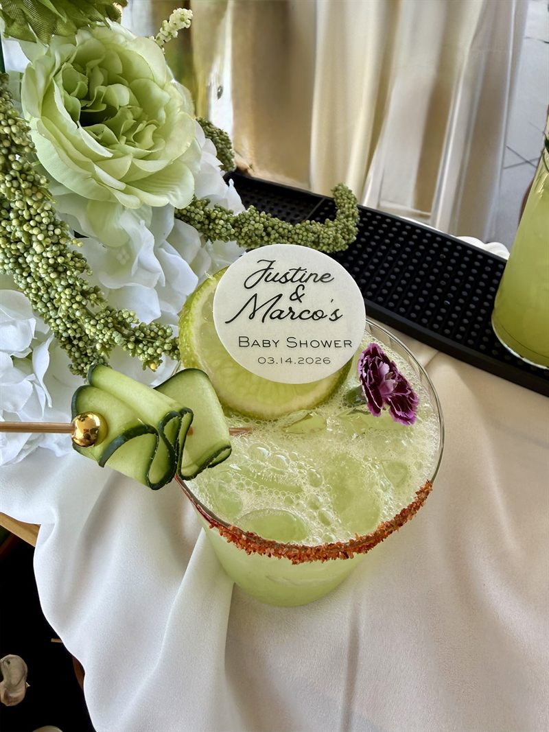 Cucumber cocktail with a chili-salt rim and a custom baby shower topper